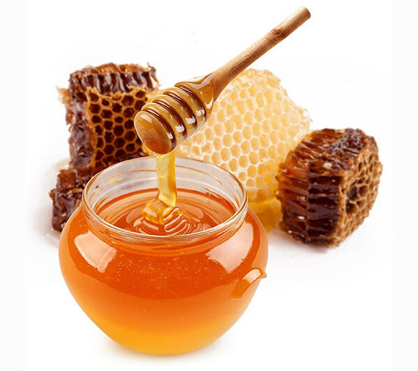 Pot of honey and wooden stick are on a table.